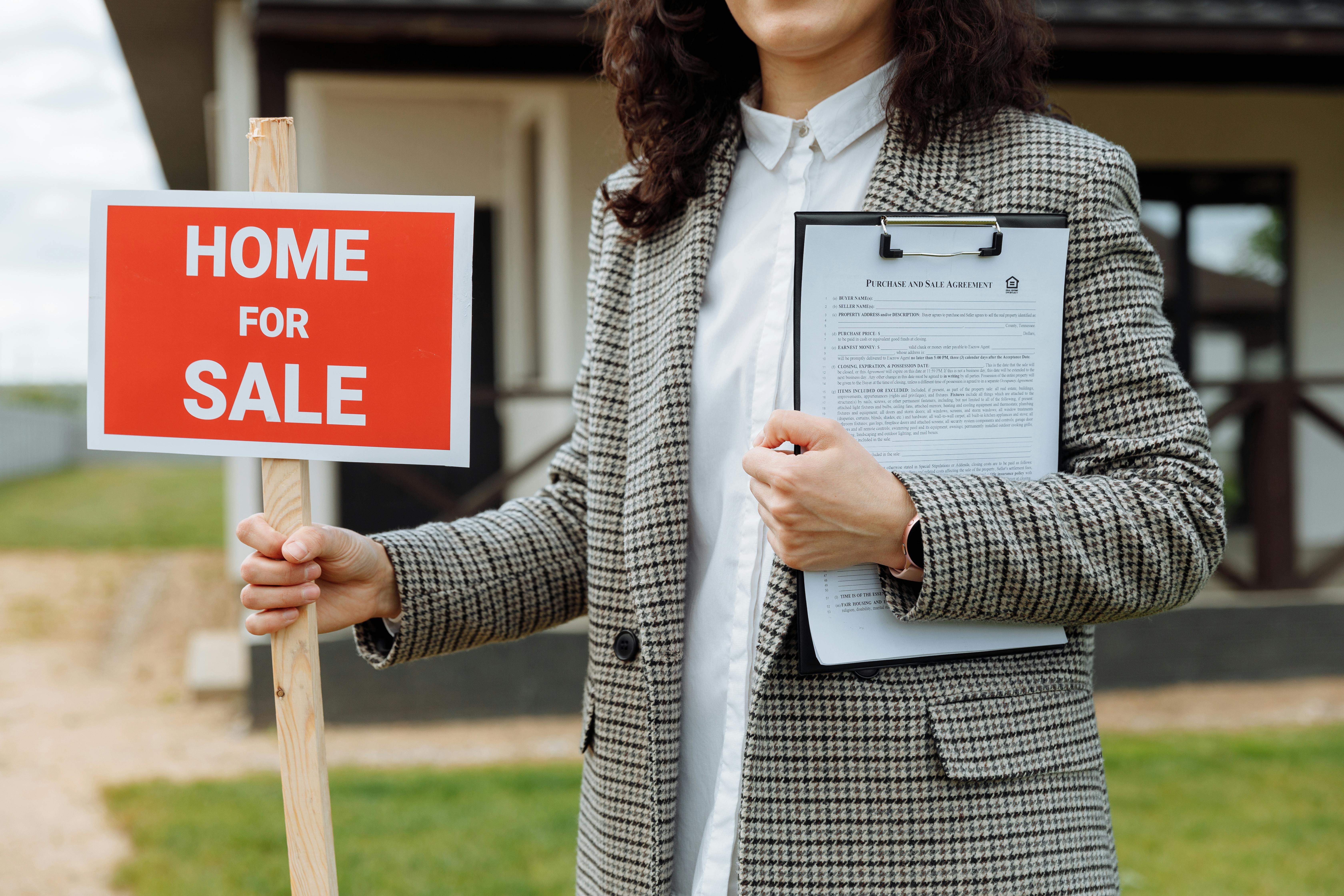 Professional real estate agent with For Sale sign in front of a luxury property